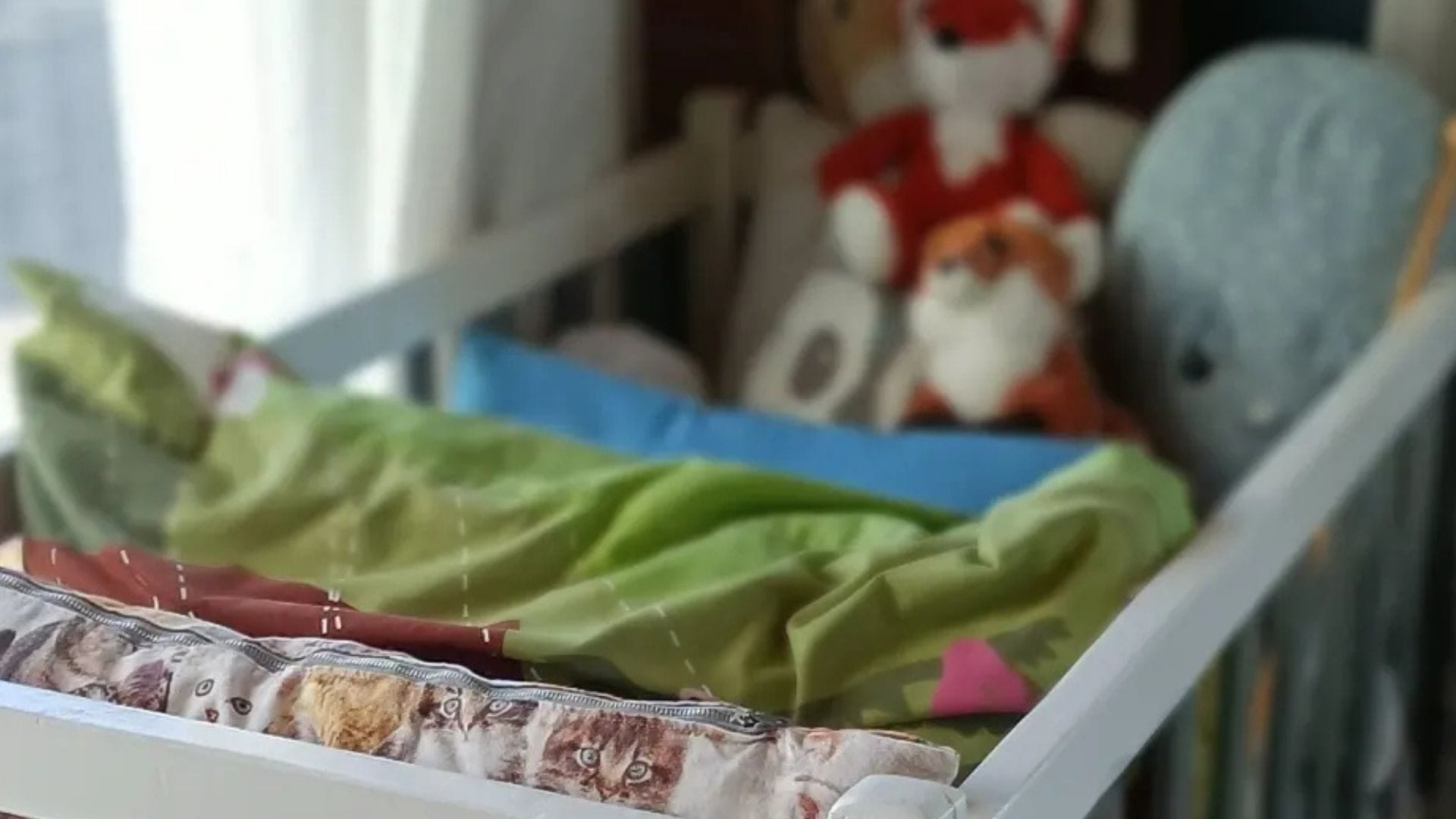 Vauvan sänky liinavaatteilla ja pehmoilla